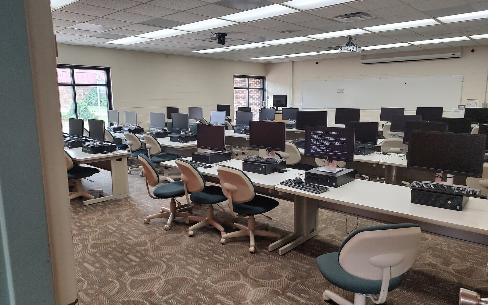 A school computer lab in session with identical terminals and a teacher present